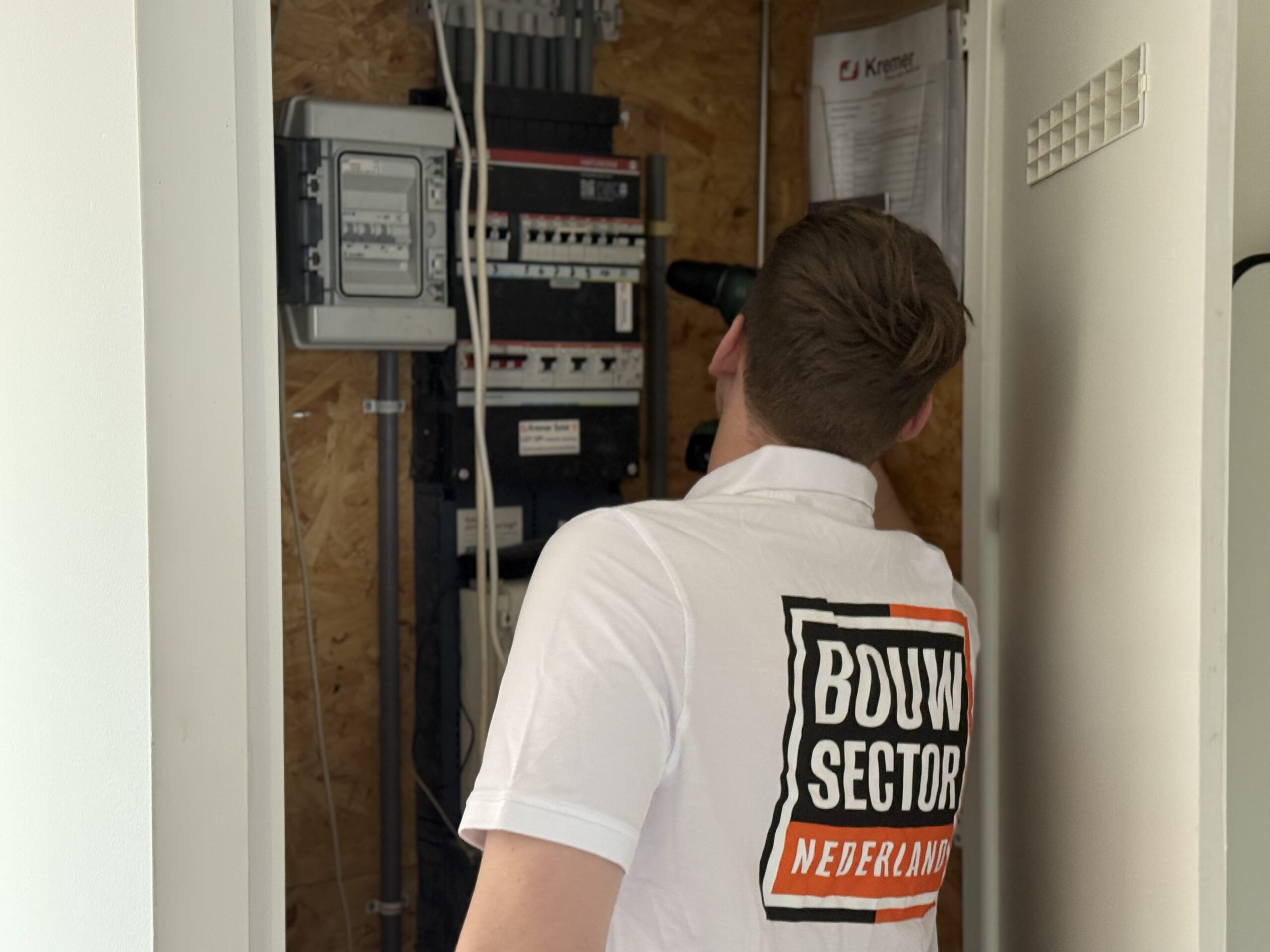 De elektricien van Bouwsector Nederland die de stoppen in de meterkast nakijkt.